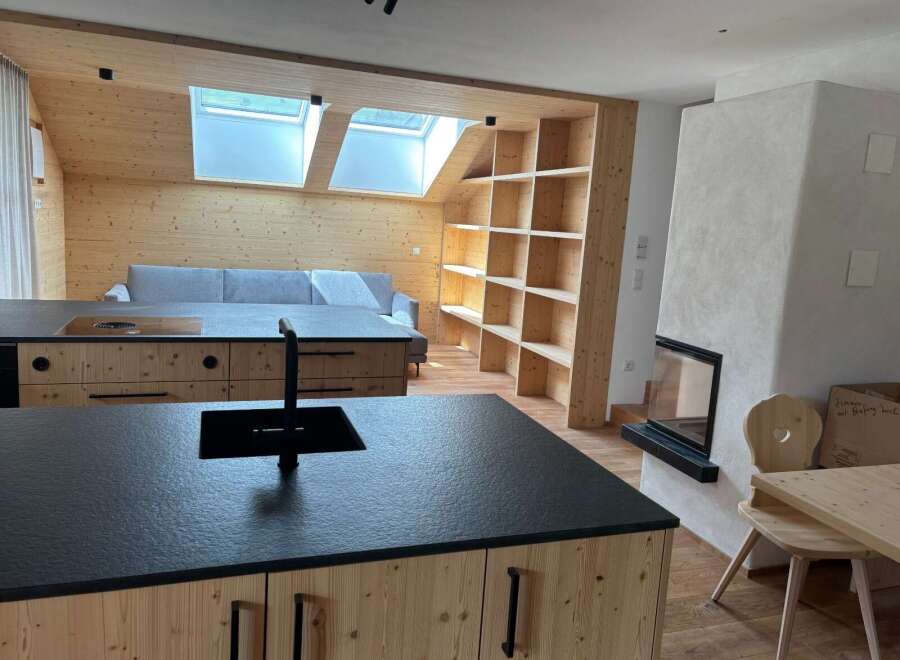 Discover modern living in this stunning property featuring a sleek kitchen island with a black countertop and a built-in sink.