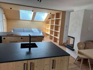 Discover modern living in this stunning property featuring a sleek kitchen island with a black countertop and a built-in sink.