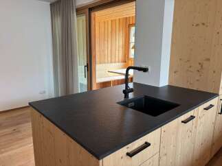 This stunning kitchen boasts a modern design with a sleek black countertop and a stylish black faucet.