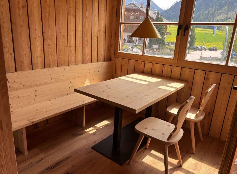 This charming dining area features a cozy wooden bench and a stylish wooden table, perfect for enjoying meals.