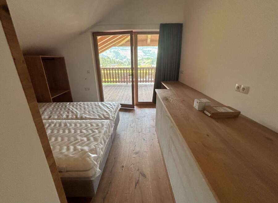 Discover a cozy bedroom with stunning mountain views! This inviting space features a comfortable bed, a wooden desk, and a balcony.