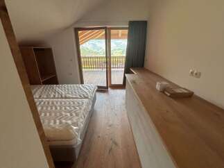 Discover a cozy bedroom with stunning mountain views! This inviting space features a comfortable bed, a wooden desk, and a balcony.
