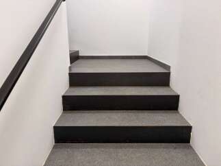 This property features a modern staircase with dark gray steps and a sleek black handrail.