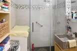 Discover this charming bathroom featuring a modern glass shower, a stylish stone sink, and ample storage solutions.