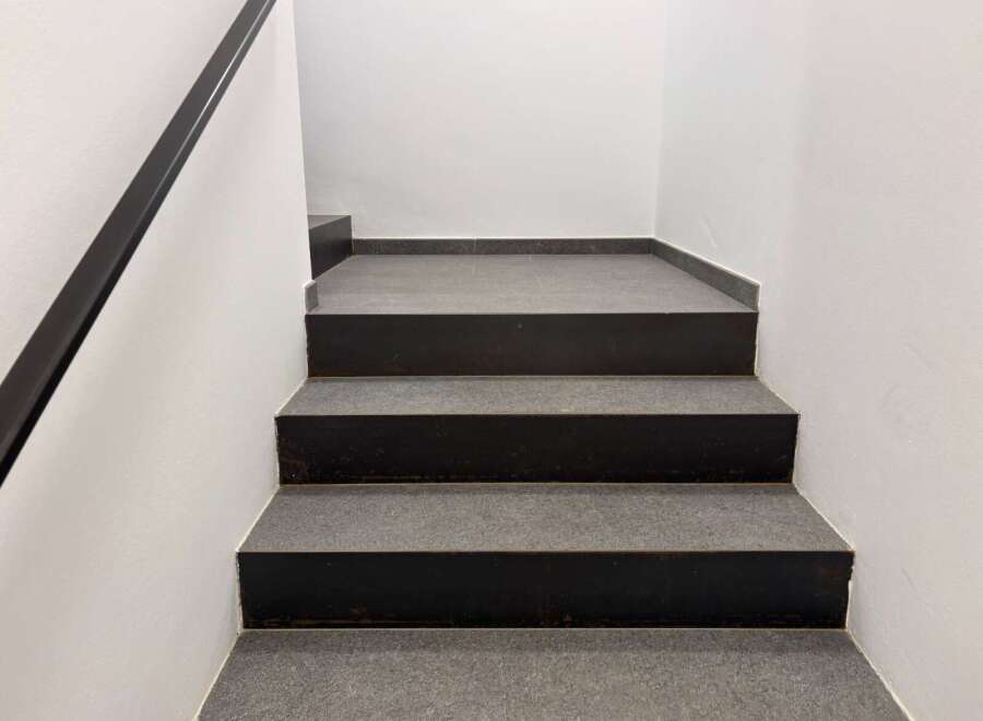 This property features a modern staircase with dark gray steps and a sleek black handrail.