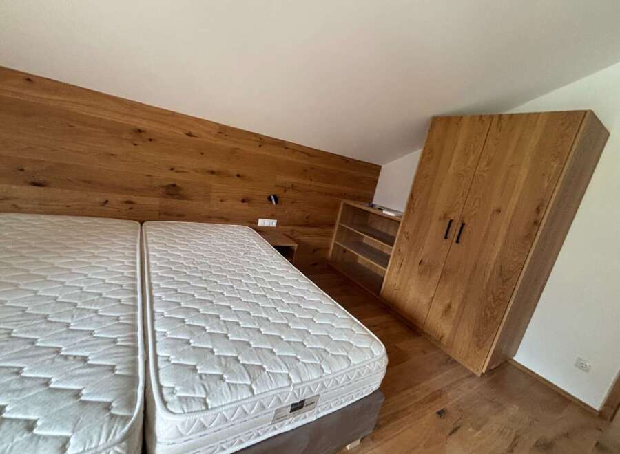This cozy bedroom features a modern design with a wooden accent wall and a comfortable bed.