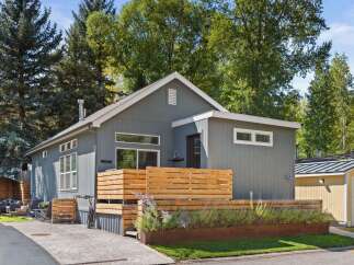 This stunning property boasts a modern design with a beautiful wooden fence and lush landscaping, creating a welcoming curb appeal.