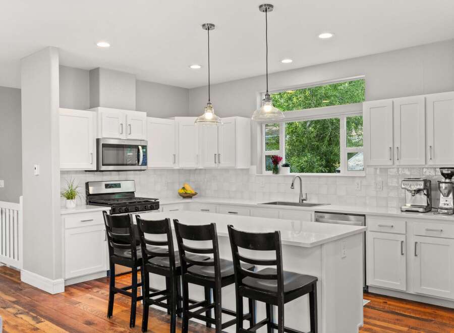 This stunning kitchen boasts a modern design with sleek white cabinetry and a spacious island, perfect for both cooking and entertaining.
