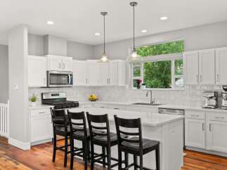 This stunning kitchen boasts a modern design with sleek white cabinetry and a spacious island, perfect for both cooking and entertaining.