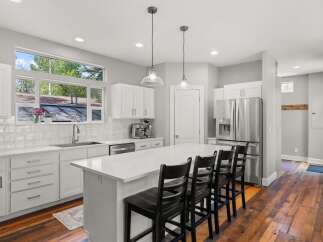 This stunning kitchen boasts a modern design with sleek white cabinetry and a spacious island, perfect for both cooking and entertaining.