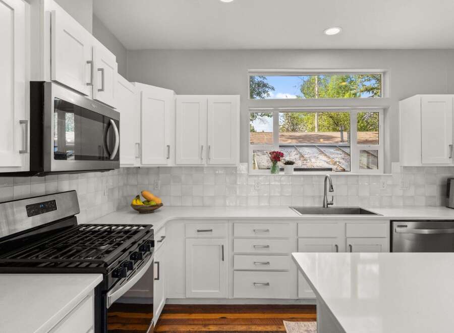 This stunning kitchen boasts a modern design with sleek white cabinetry and countertops, creating a bright and inviting atmosphere.