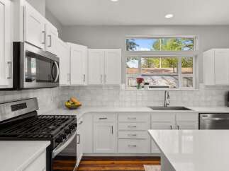 This stunning kitchen boasts a modern design with sleek white cabinetry and countertops, creating a bright and inviting atmosphere.