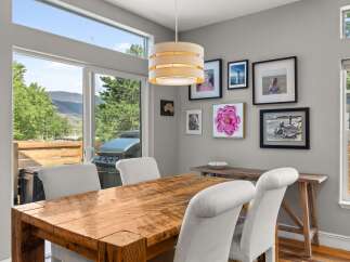 This stunning dining area boasts a rustic wooden table and elegant white chairs, perfect for hosting gatherings.