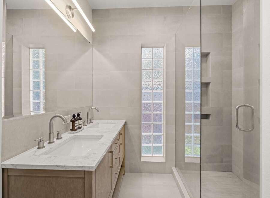 Step into luxury with this stunning bathroom featuring a sleek double vanity and a spacious glass-enclosed shower.