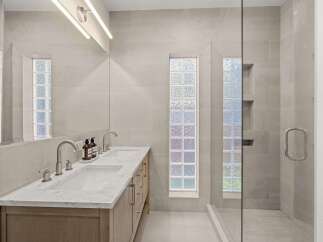 Step into luxury with this stunning bathroom featuring a sleek double vanity and a spacious glass-enclosed shower.