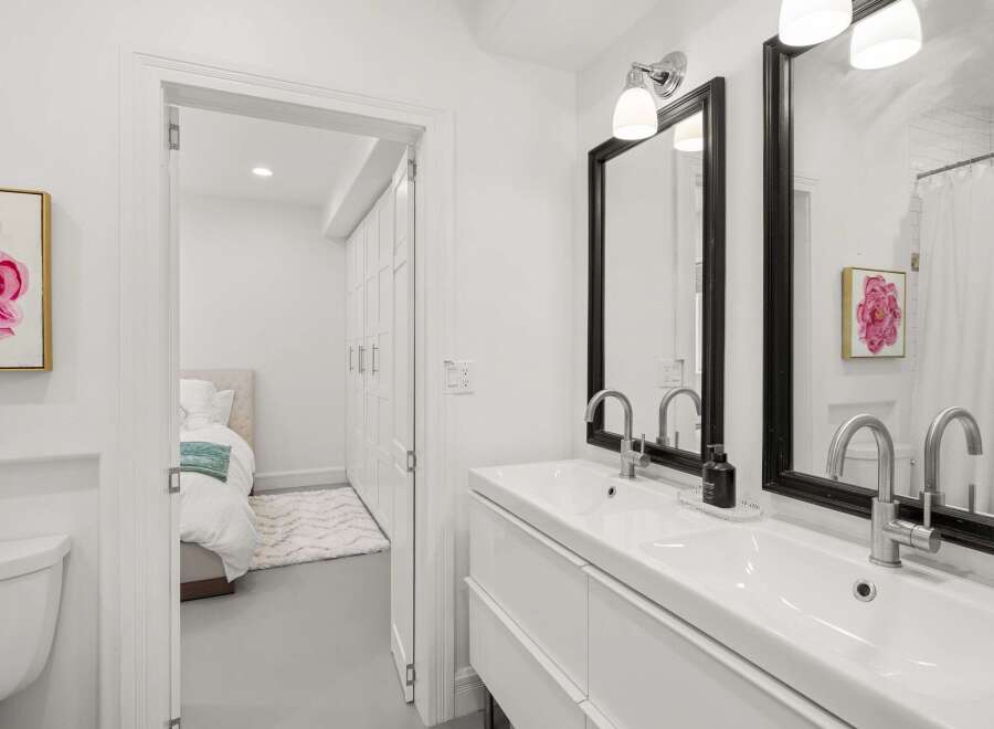 Step into a bright and modern bathroom, featuring a sleek double vanity and stylish black-framed mirrors.
