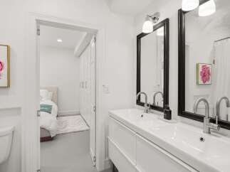 Step into a bright and modern bathroom, featuring a sleek double vanity and stylish black-framed mirrors.