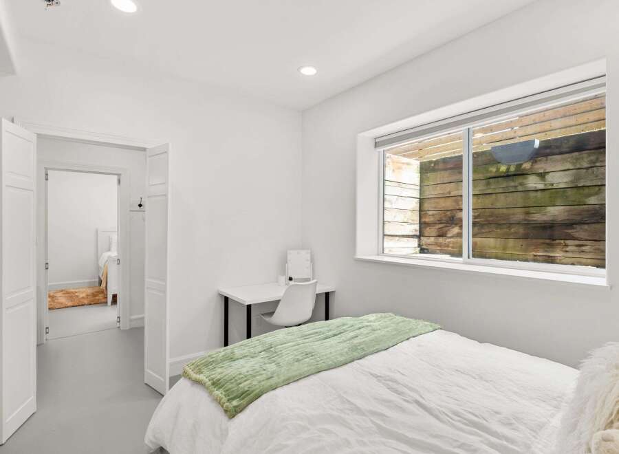 This bright and airy bedroom offers a serene retreat with its minimalist design and ample natural light.