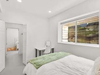 This bright and airy bedroom offers a serene retreat with its minimalist design and ample natural light.