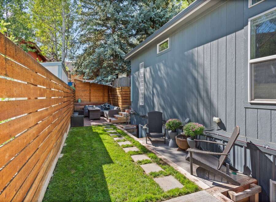 Enjoy outdoor living in this charming backyard oasis! This property features a beautifully landscaped yard with a lush green lawn and a stone pathway.