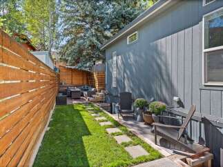 Enjoy outdoor living in this charming backyard oasis! This property features a beautifully landscaped yard with a lush green lawn and a stone pathway.