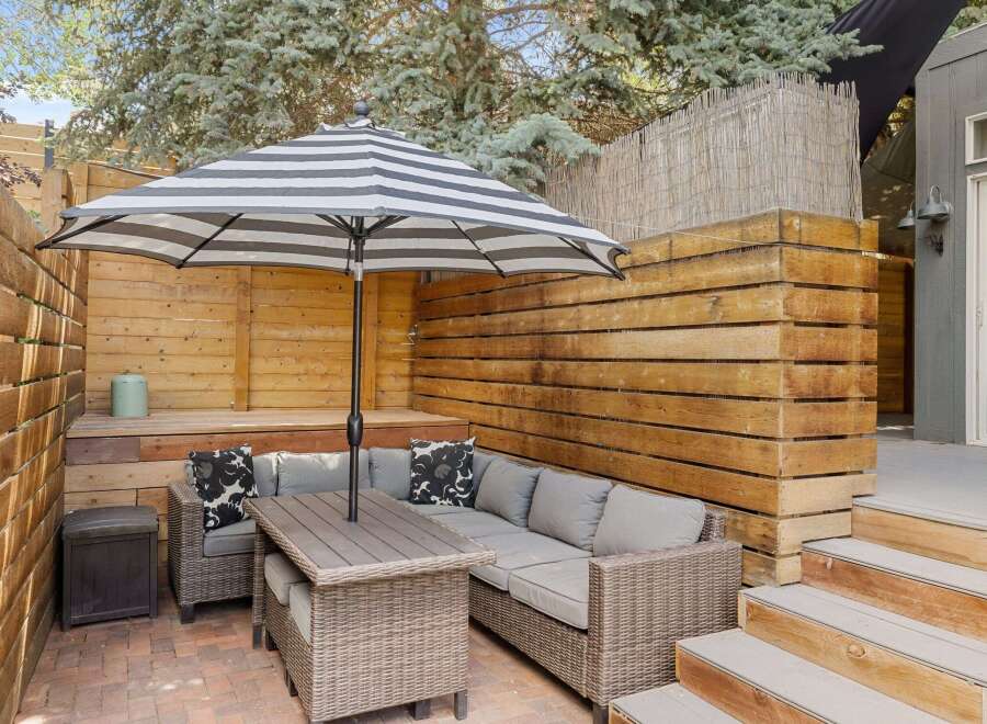 Enjoy outdoor living in this beautiful patio space! Featuring a stylish striped umbrella, comfortable seating, and a charming brick patio, this area is perfect for relaxation and entertaining.