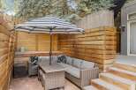 Enjoy outdoor living in this beautiful patio space! Featuring a stylish striped umbrella, comfortable seating, and a charming brick patio, this area is perfect for relaxation and entertaining.