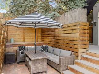 Enjoy outdoor living in this beautiful patio space! Featuring a stylish striped umbrella, comfortable seating, and a charming brick patio, this area is perfect for relaxation and entertaining.