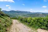 Discover the beauty of nature with this stunning property! The image showcases a scenic view of a mountain range, a dirt road, and lush greenery.