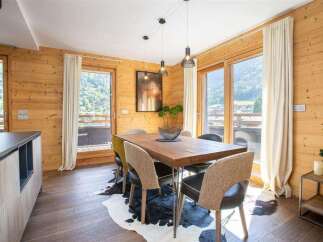 Experience the charm of this stunning property, featuring a beautifully designed dining area with a rustic wooden table and stylish chairs.