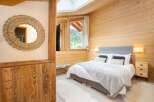 Experience the warmth of this cozy bedroom, featuring stunning wood paneling and a luxurious bed.