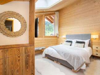 Experience the warmth of this cozy bedroom, featuring stunning wood paneling and a luxurious bed.