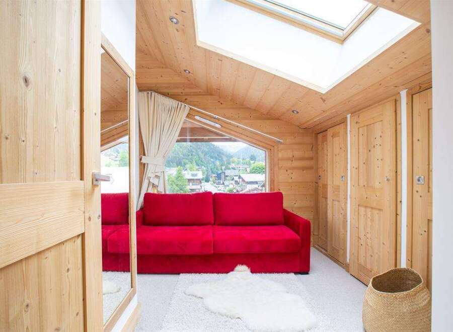 Discover the charm of this cozy living space, featuring a vibrant red sofa and a warm, inviting wooden interior.