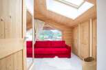 Discover the charm of this cozy living space, featuring a vibrant red sofa and a warm, inviting wooden interior.