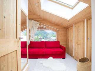 Discover the charm of this cozy living space, featuring a vibrant red sofa and a warm, inviting wooden interior.