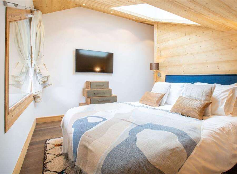 This cozy bedroom features a unique design with wooden accents and a skylight, creating a warm and inviting atmosphere.