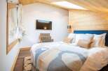 This cozy bedroom features a unique design with wooden accents and a skylight, creating a warm and inviting atmosphere.
