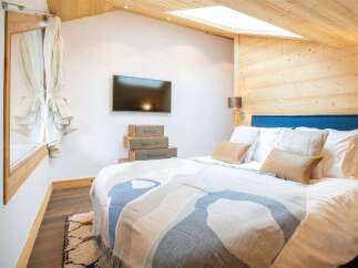 This cozy bedroom features a unique design with wooden accents and a skylight, creating a warm and inviting atmosphere.