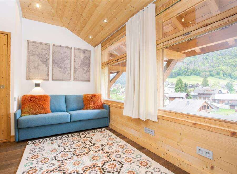 Experience the charm of this cozy living space, featuring a comfortable blue sofa adorned with vibrant orange pillows.