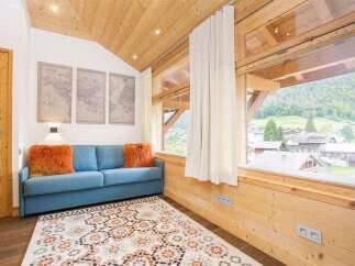 Experience the charm of this cozy living space, featuring a comfortable blue sofa adorned with vibrant orange pillows.