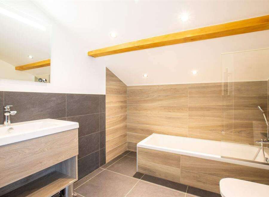 This modern bathroom features a sleek design with a wooden vanity and a luxurious bathtub.