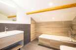 This modern bathroom features a sleek design with a wooden vanity and a luxurious bathtub.