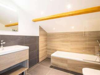 This modern bathroom features a sleek design with a wooden vanity and a luxurious bathtub.