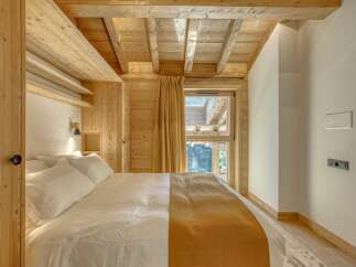 This cozy bedroom features a warm, inviting atmosphere with its wooden ceiling and walls.