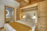 Experience the warmth and charm of this cozy bedroom, featuring stunning wooden accents and a luxurious bed.