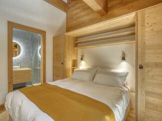 Experience the warmth and charm of this cozy bedroom, featuring stunning wooden accents and a luxurious bed.
