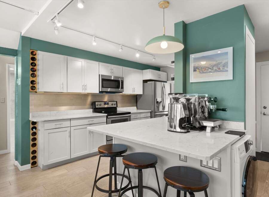 This stunning kitchen boasts modern design with sleek white cabinetry, stainless steel appliances, and a beautiful quartz countertop.