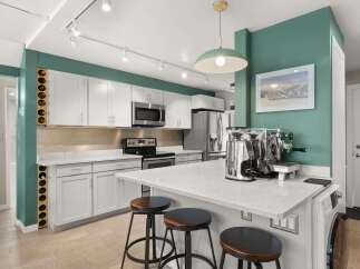 This stunning kitchen boasts modern design with sleek white cabinetry, stainless steel appliances, and a beautiful quartz countertop.