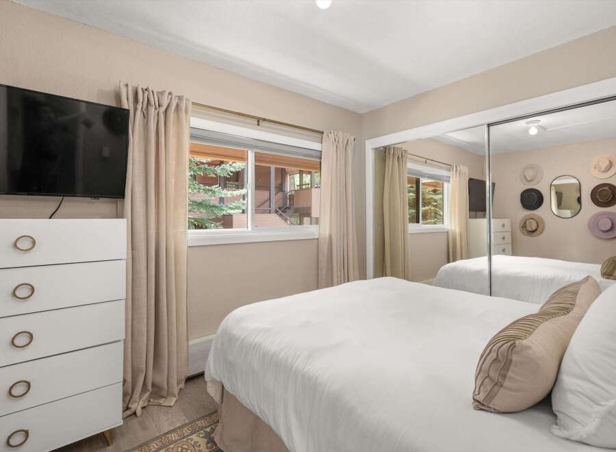 This inviting bedroom offers a serene retreat with its neutral color palette and ample natural light.