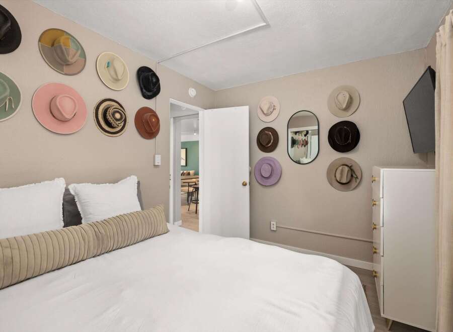 This charming bedroom features a unique wall decor of hats, adding a touch of personality and style.